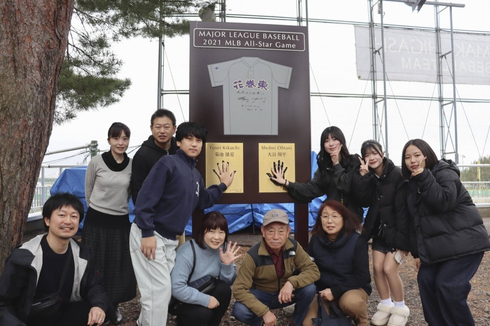 People have their photos taken on Sunday in front of a monument with Shohei Ohtani's handprint near the baseball field of Hanamaki Higashi high school in Iwate Prefecture.