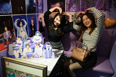 Yuka Tada and her friend pose for a photograph at a BTS fan cafe in Tokyo.