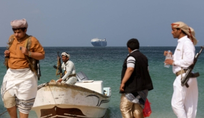 Armed men stand on a beach as the Galaxy Leader commercial ship, seized by Yemen's Houthis last month, is anchored off the coast of al-Salif, Yemen, on Dec. 5.