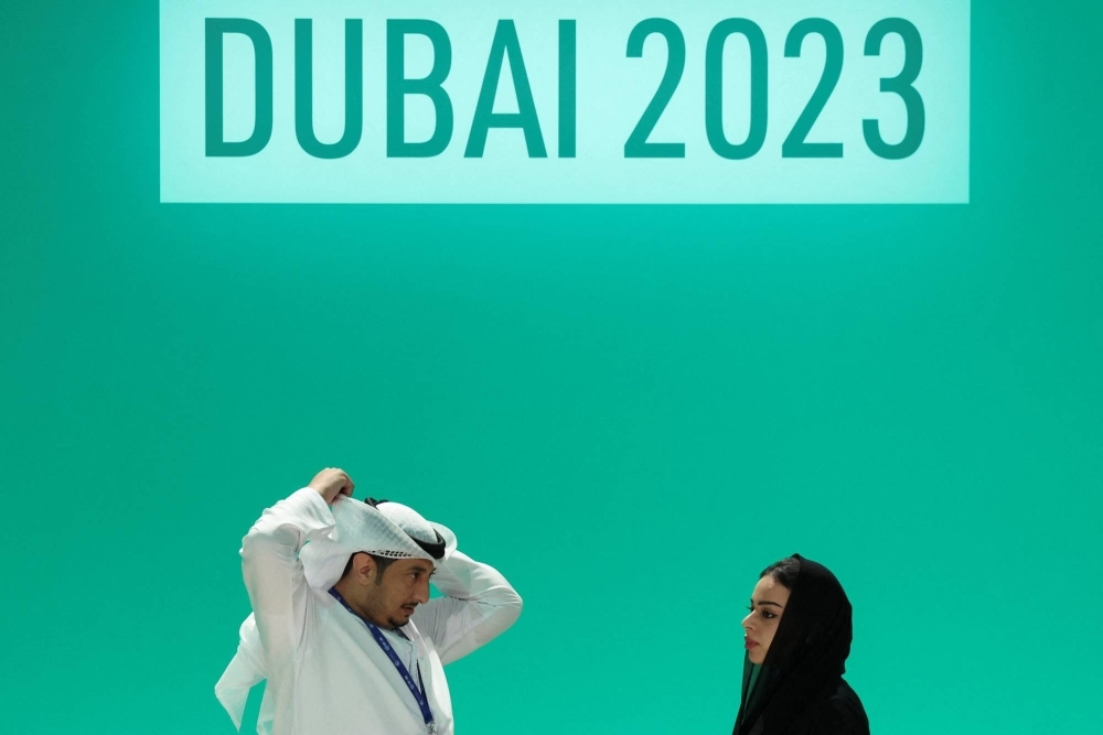 People stand on a stage at the COP28 conference in Dubai after a draft of a negotiation deal was released on Wednesday. 