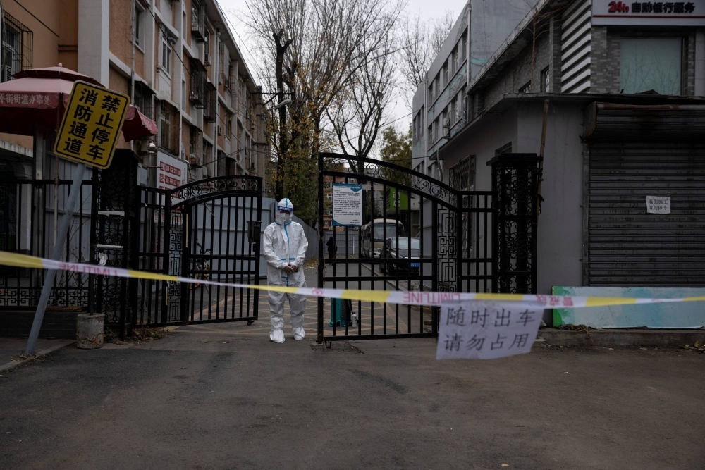 An epidemic-prevention worker in a protective suit stands guard at the gate of a residential compound in Beijing in November last year.