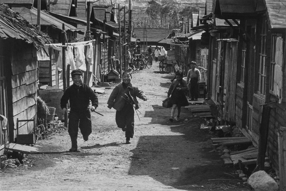 Children run down a street in the Oimawashi district of Sendai in about 1955.
