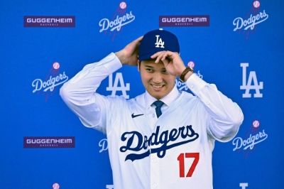 Shohei Ohtani puts on a Dodgers cap and uniform during his introductory news conference at Dodgers Stadium in Los Angeles on Thursday.