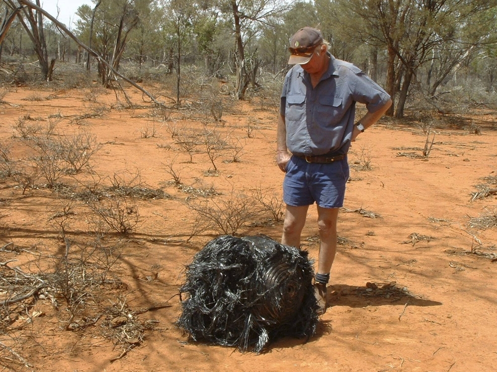 Un granjero australiano se encuentra junto a una bola de metal retorcido, supuestamente basura espacial caída. Un granjero australiano se encuentra junto a una bola de metal retorcido, supuestamente basura espacial caída.