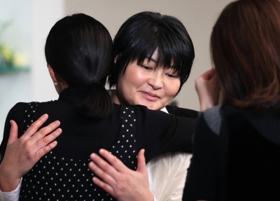 Nobuko, younger sister of Kotaro Nishizawa, who died at his clinic in Osaka during an arson attack, hugs one of the audience members following a memorial concert for the victims held in the city on Dec. 3.