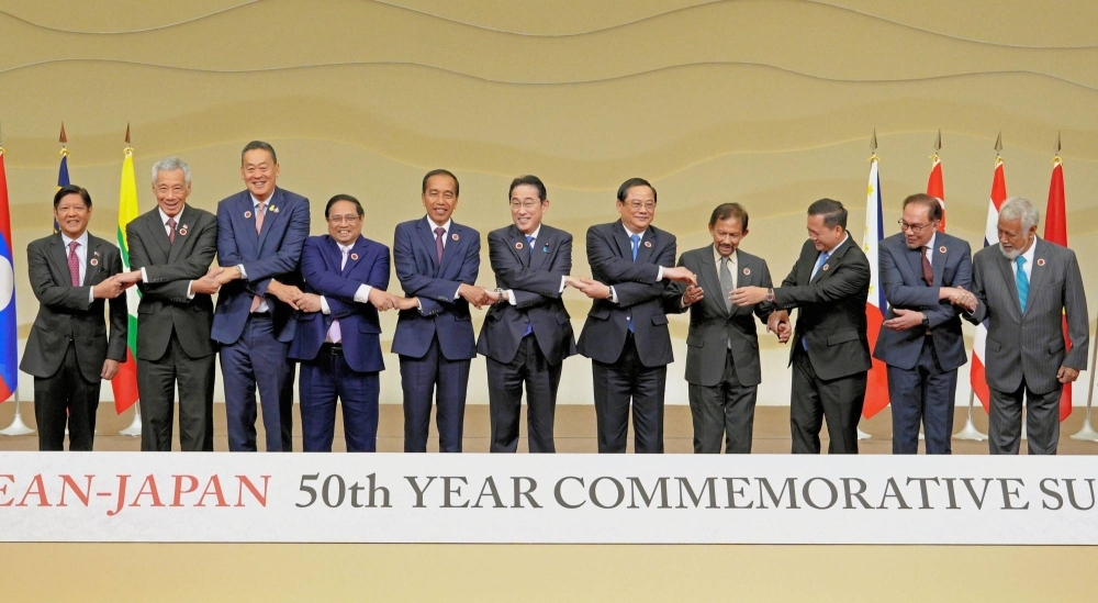 Prime Minister Fumio Kishida (center) and ASEAN leaders join hands during a photo session during a summit meeting in Tokyo on Sunday.