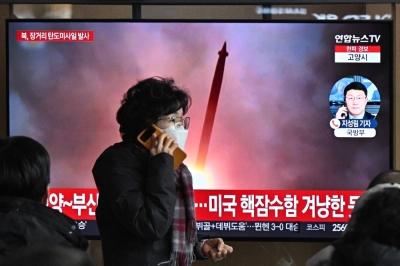A woman walks past a television screen showing a news broadcast with file footage of a North Korean missile test, at the main railway station in Seoul on Monday.