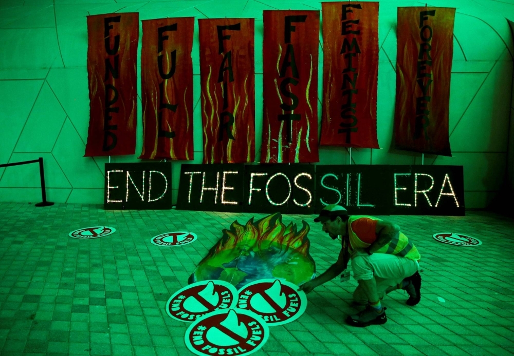 A climate activist arranges artwork expressing opposition to fossil fuels at Dubai's Expo City during the United Nations Climate Change Conference COP28 in Dubai on Dec. 12.