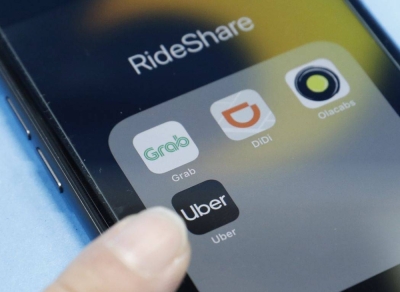 Ride-sharing apps (clockwise from bottom) Uber, Grab, Didi and Ola Cabs are seen on a smartphone display.