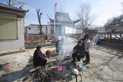 People gather around a fire on Wednesday to keep warm outside a local mosque after an earthquake in northwest China's Gansu province on Monday.