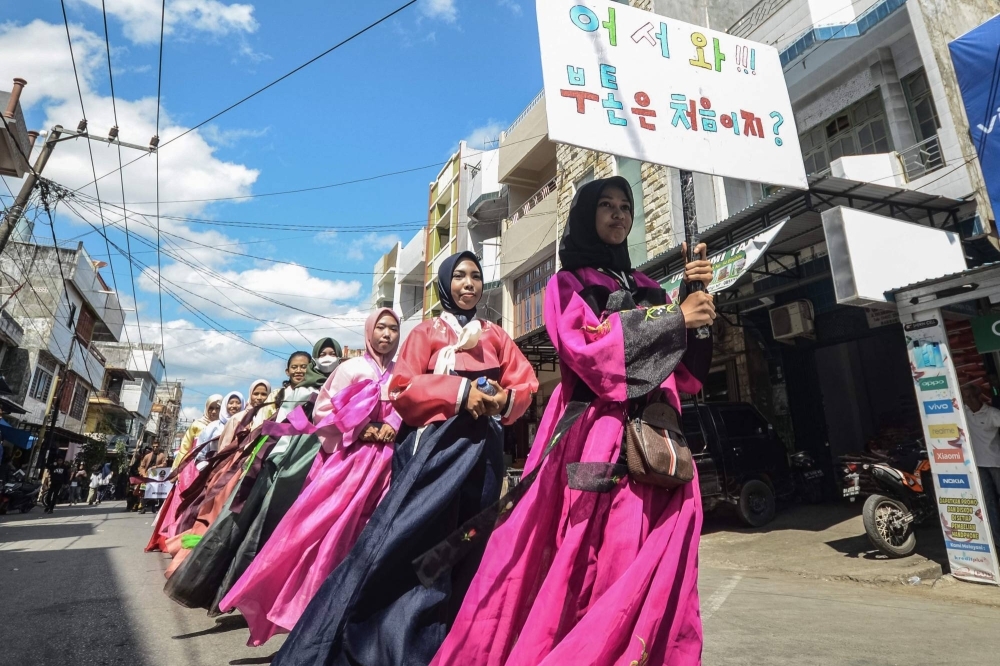 Participants in traditional Korean attire holds signs using the Korean Hangul script — used to document the language of the Cia-Cia ethnic group, which has no written form — on Buton island, Southeast Sulawesi, Indonesia, on Oct. 14.