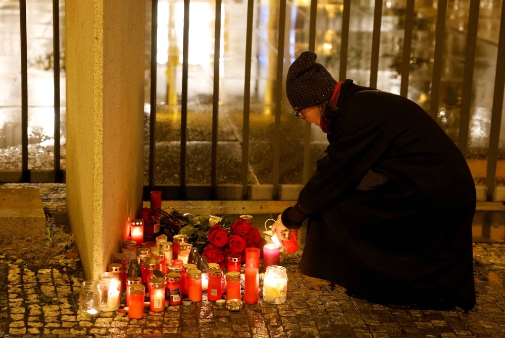 A woman lights a candle in front of the Charles University main building following a shooting at one of the university's buildings in Prague on Thursday.