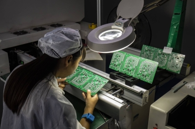 An employee inspects integrated circuit boards at a factory in Suzhou, China.