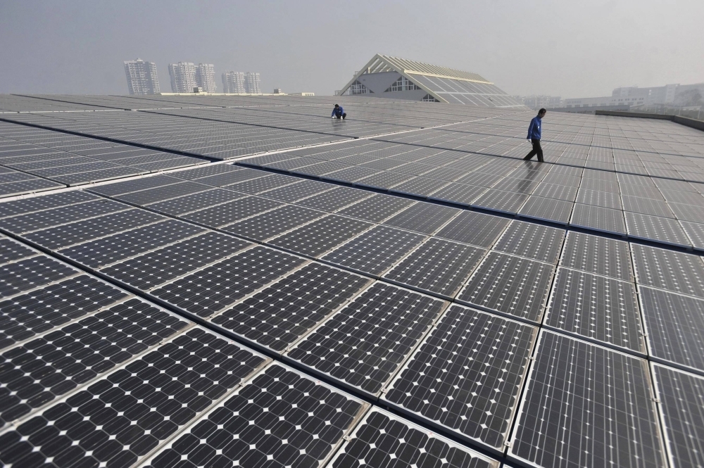 Technicians work on a roof covered with solar panels at a plant in Wuhan, China. 