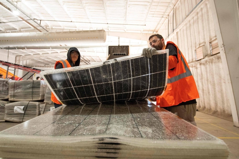 Workers push damaged solar panels into a machine to be recycled at the We Recycle Solar plant in Yuma, Arizona.