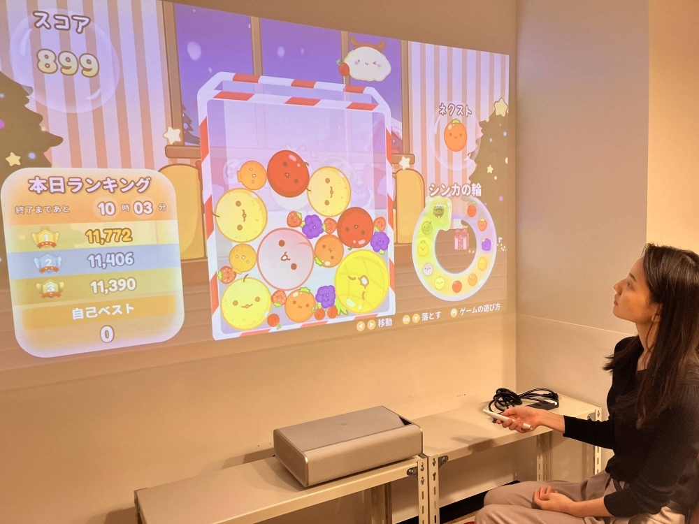 An Aladdin X staff member plays Suika Game on its home projector in Tokyo on Friday. Suika Game was originally developed for the company's line of home projectors.