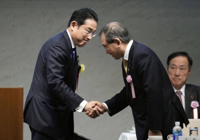 Prime Minister Fumio Kishida (left) shakes hands with Masakazu Tokura, head of Keidanren, during the business lobby's meeting in Tokyo on Monday.