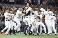 Designated hitter and closer Shohei Ohtani (center) and catcher Yuhei Nakamura are mobbed by their Samurai Japan teammates after Ohtani struck out American slugger Mike Trout to clinch Japan’s third World Baseball Classic and first since 2009, at LoanDepot Park in Miami on March 21. | Rhona Wise - USA TODAY Sports / via Reuters