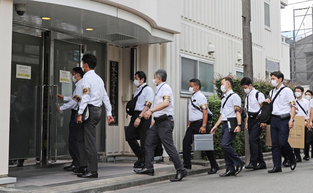 Tokyo police raid the dormitory of the Nihon University football team in the capital’s Nakano Ward on Aug. 3. Several players from the team were involved in a drug scandal, leading to the storied club’s disbandment later in the year.