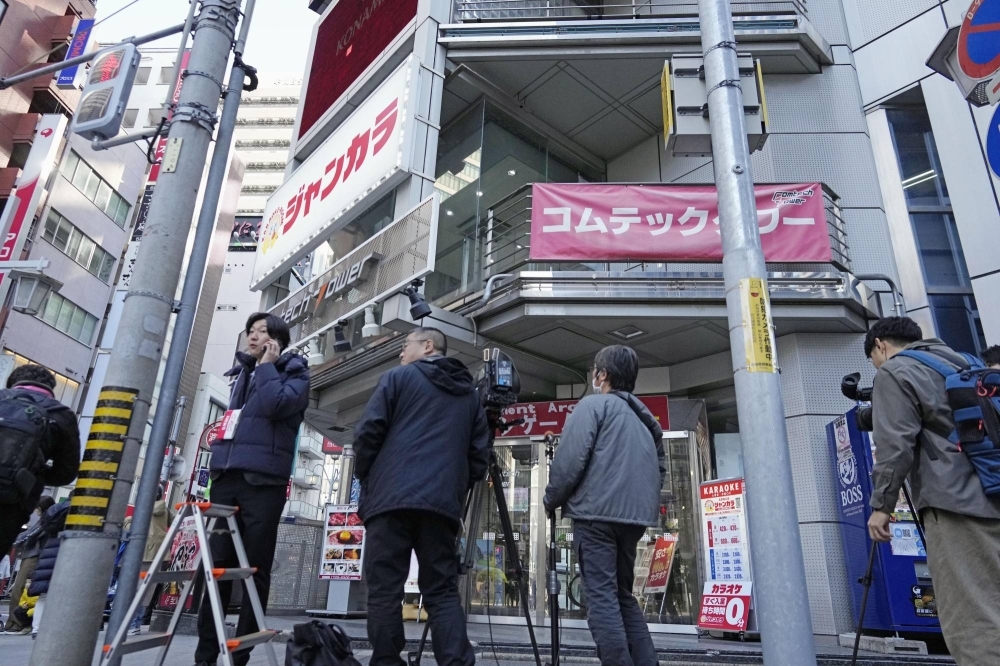 Reporters gather outside a building housing a karaoke store in Nagoya where a stabbing occurred on Tuesday.