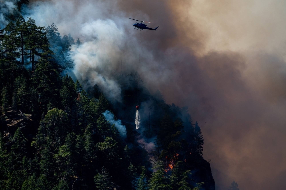 A helicopter waterbombs fires near Port Alberni, British Columbia, on June 6. Record wildfires devastated huge swaths of forest in Canada, with scientists saying the disasters were made worse by climate change.