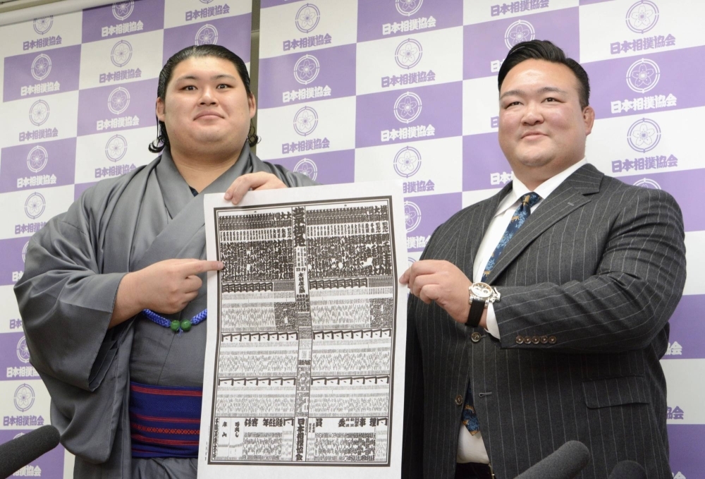 Onosato (left) and Nishonoseki stablemaster display the rankings list on Monday for the upcoming New Year's Grand Sumo Tournament, during which the highly touted Onosato will make his top-division debut.