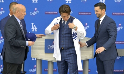 Dodgers President Stan Kasten (left) and general manager Brandon Gomes watch as Yoshinobu Yamamoto dons his No. 18 jersey during an introductory news conference at Dodger Stadium on Wednesday. 