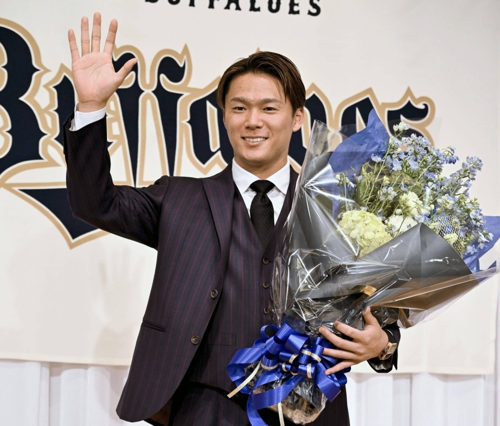 Former Orix Buffaloes ace Yoshinobu Yamamoto waves during a news conference in Osaka on Saturday. 