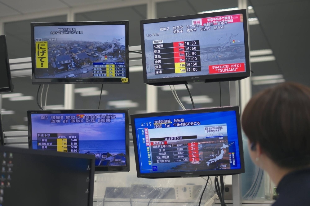 A man watches TV screens in Osaka showing news of a powerful earthquake that hit the Noto Peninsula area in Ishikawa Prefecture on Monday.