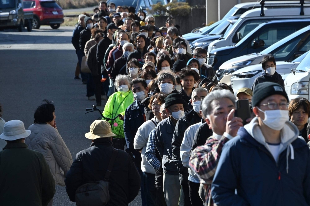 People line up around the town hall in Shika, Ishikawa Prefecture, as they wait to receive water at a distribution point on Tuesday. 