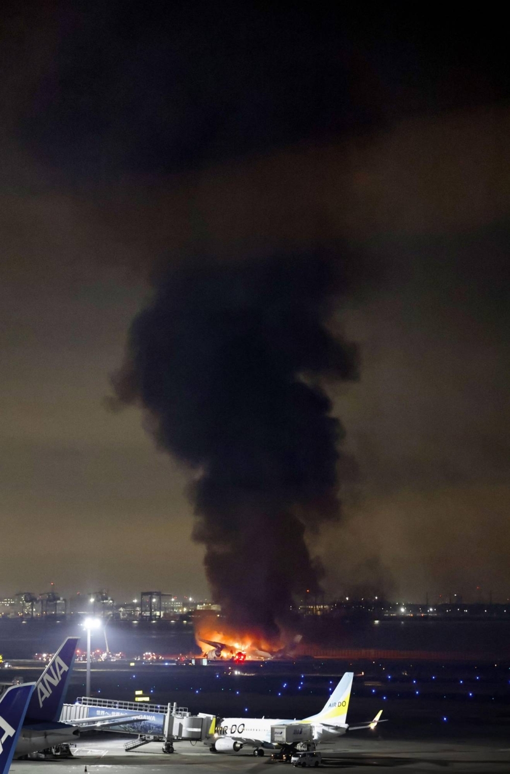 A huge column of smoke as a Japan Airlines plane is engulfed in flames at Haneda Airport on Tuesday. 