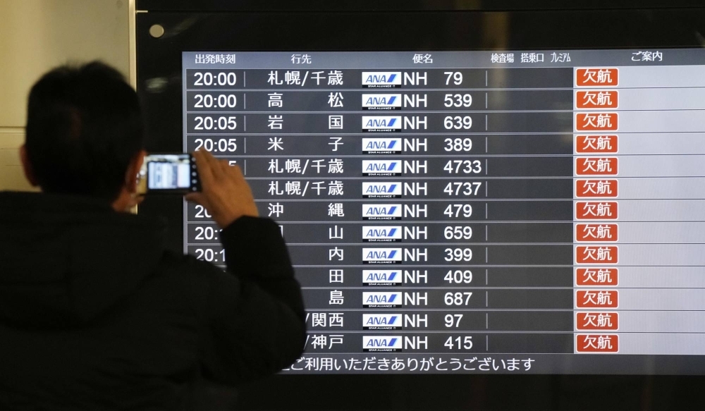 A flight board at Haneda Airport shows all flights as canceled after all runways were closed following a deadly collision between two planes. 