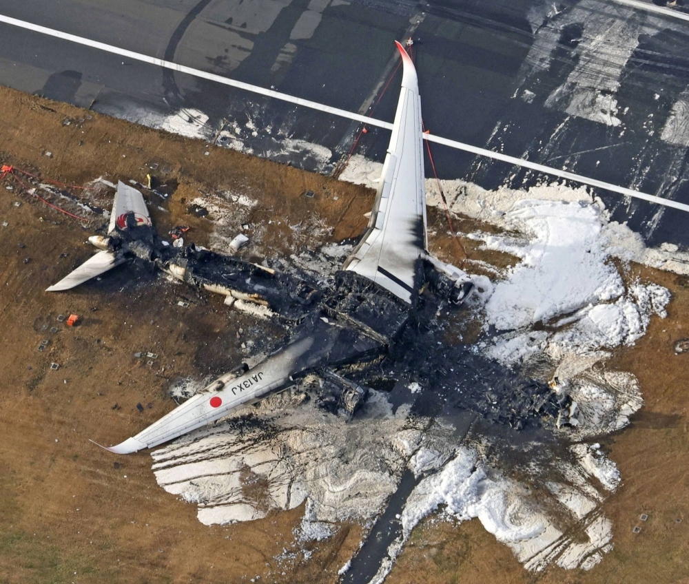 An aerial view shows the burnt Japan Airlines Airbus A350 plane after a collision with a Japan Coast Guard aircraft at Haneda Airport in Tokyo