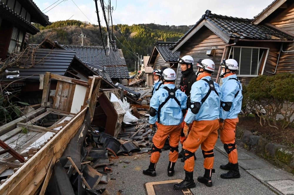 Firefighters inspect collapsed wooden houses in Wajima, Ishikawa Prefecture, on Tuesday, a day after a major 7.6 magnitude earthquake struck the Noto region in the prefecture.
