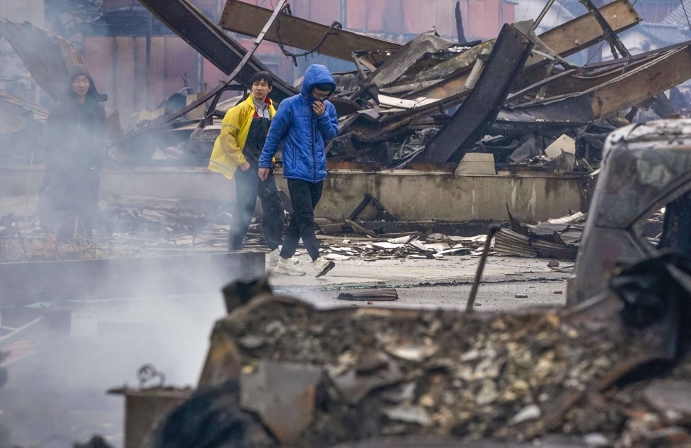 People inspect the extent of damage from fires in Wajima on Wednesday.
