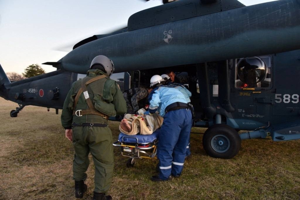 Self-Defense Force helicopter crew members transport a patient in Suzu, Ishikawa Prefecture, on Tuesday.