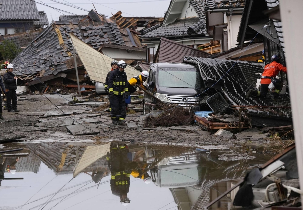 Firefighters inspect collapsed houses in Suzu, Ishikawa Prefecture.