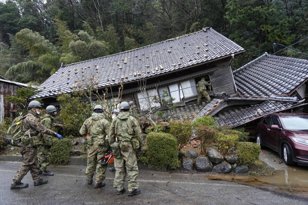 Japanese Self-Defense Force soldiers search a collapsed house in Suzu, Ishikawa Prefecture.