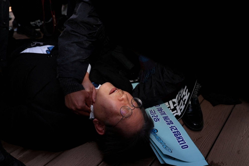 Opposition leader Lee Jae-myung falls after being stabbed in the neck with a knife during his visit to Busan, South Korea, on Tuesday.