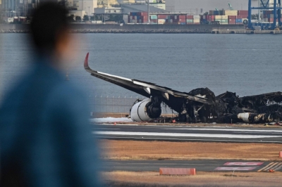 A man looks out at the burnt wreckage of a Japan Airlines passenger plane on the tarmac at Haneda Airport in Tokyo on Wednesday.