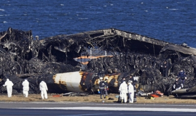 Authorities examine the burned wreckage of a Japan Airlines passenger plane at Haneda Airport in Tokyo on Thursday.