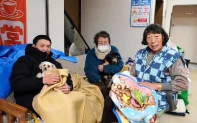 Tomoyoshi Taniguchi (left), Ryuko Neya (center) and Taiko Minami with pets at the Misogichiku Community Center in Nanao, Ishikawa Prefecture. Pet owners were told they could not enter the shelter room and had to stay in hallways and the entrance hall.