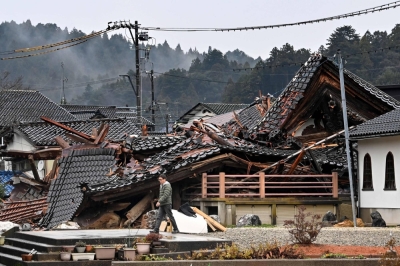 A man walks past a collapsed house in Anamizu Town, Ishikawa Prefecture, on Wednesday, after an earthquake struck the Noto region of the prefecture on New Year's Day.