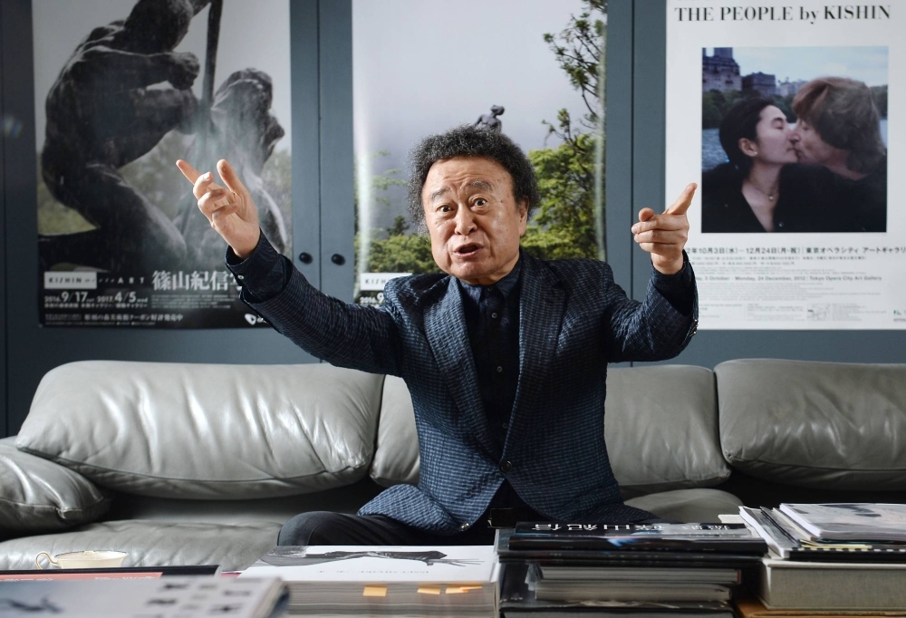 Kishin Shinoyama speaks during an interview in Tokyo in September 2016 with posters of his works in the background.