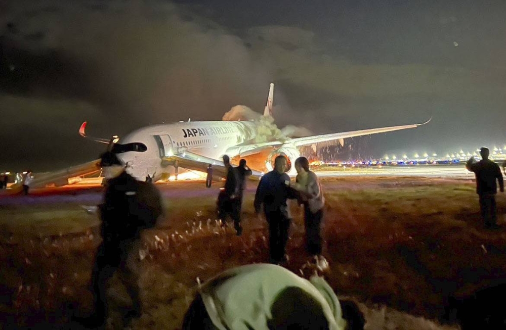 A photo supplied by a passenger shows passengers evacuating as a Japan Airlines aircraft burns on a runway at Tokyo's Haneda Airport on Tuesday.
