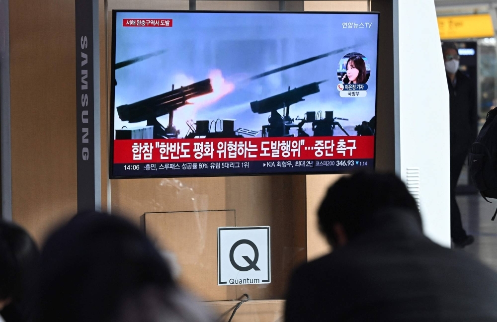 People watch a news broadcast showing file footage of North Korea firing artillery, at a railway station in Seoul on Friday.