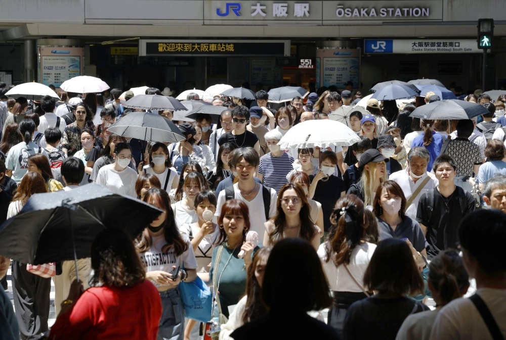 People holding parasols amid scorching heat in Osaka's Umeda district in July.
