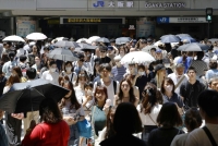 People holding parasols amid scorching heat in Osaka's Umeda district in July. | Kyodo
