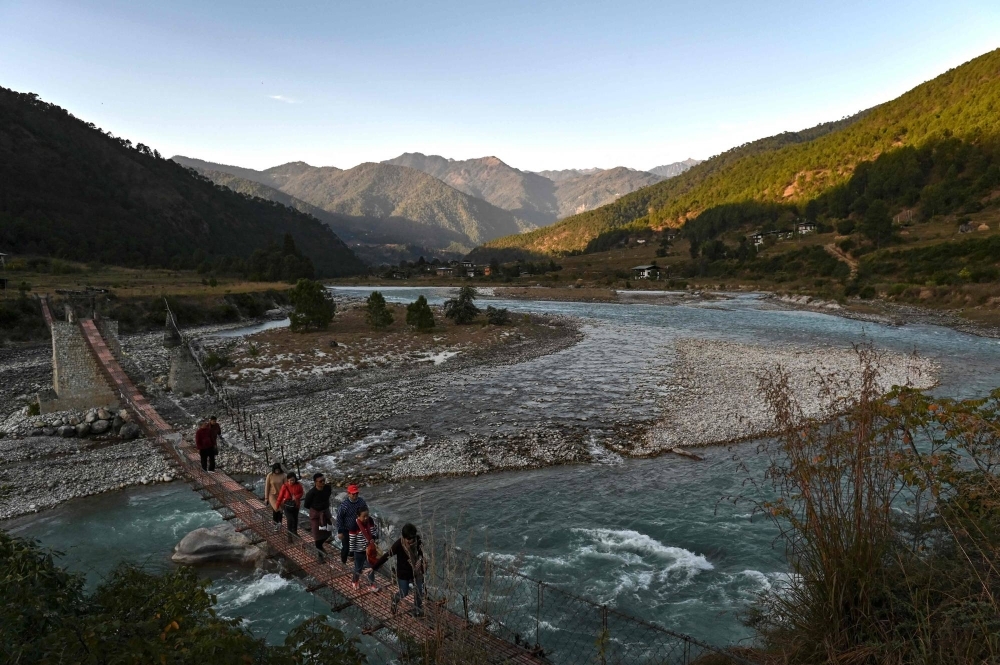 Tourists walking across a suspension bridge over the Puna Tsang Chhu River in Punakha province in Bhutan in December 2019. Tourists walking across a suspension bridge over the Puna Tsang Chhu River in Punakha province in Bhutan in December 2019.