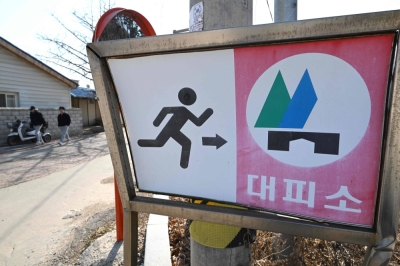 South Korean residents walk past a shelter sign at a village on Yeonpyeong Island on Saturday. 